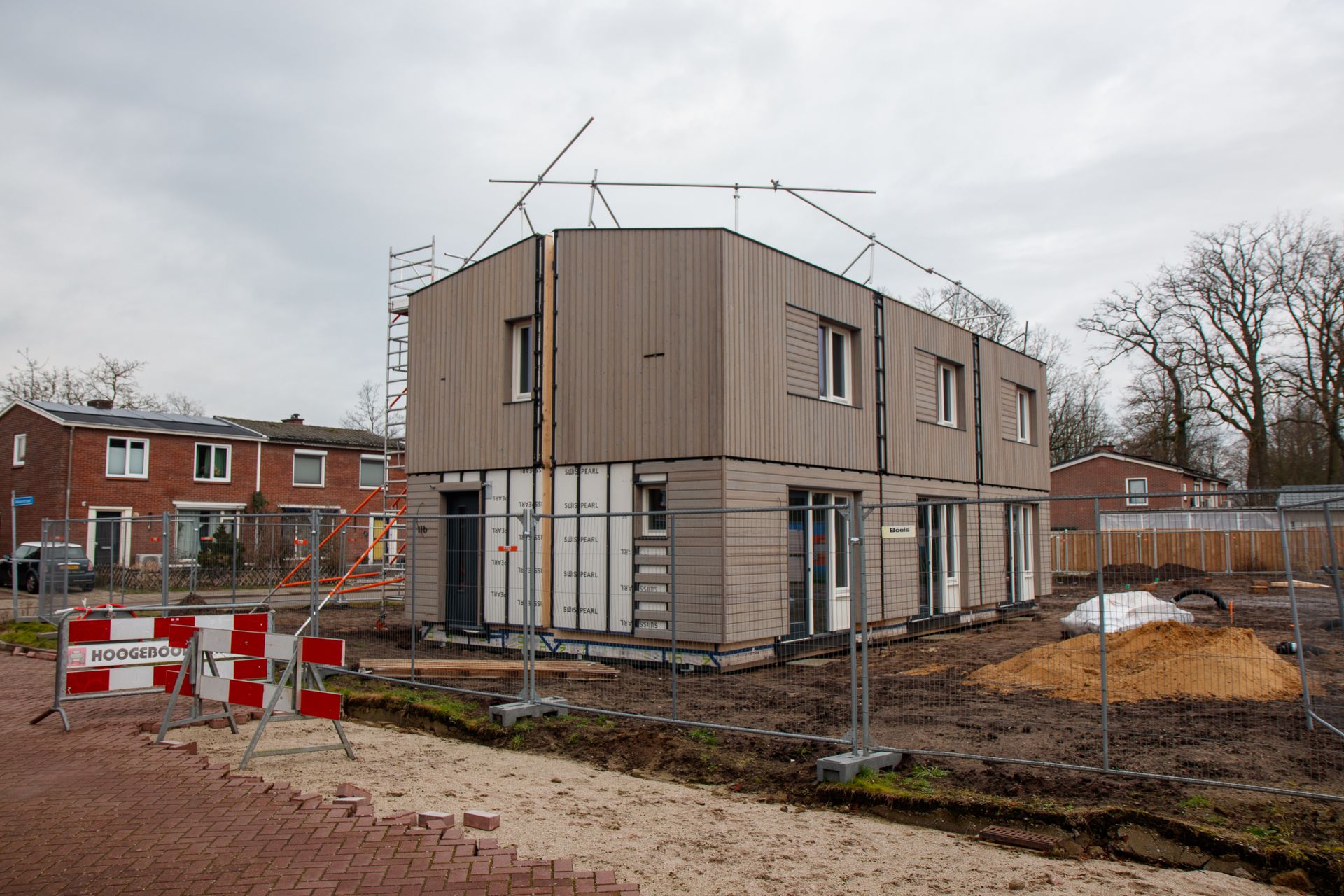 Nieuwbouwwoning in de steigers achter bouwhekken, illustratief bij de sterk verschillende bouwleges per gemeente
