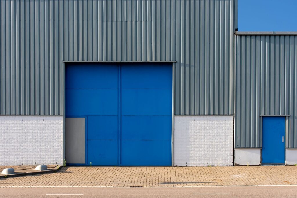 Bedrijfshal met blauwe overheaddeur, illustratief bij de verhuurde bedrijfsruimte in Rotterdam op Nieuw-Kralingen Businesspark