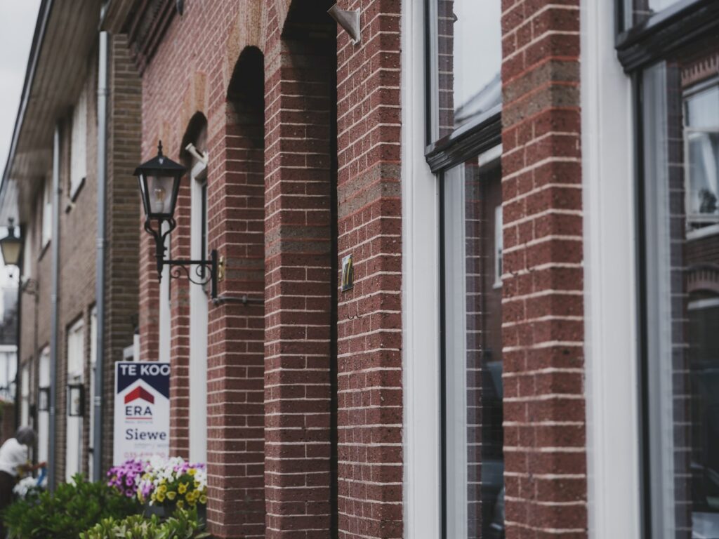Nederlandse straat met een te-koop-bord van een makelaar, illustratief bij het biedingsproces op de woningmarkt