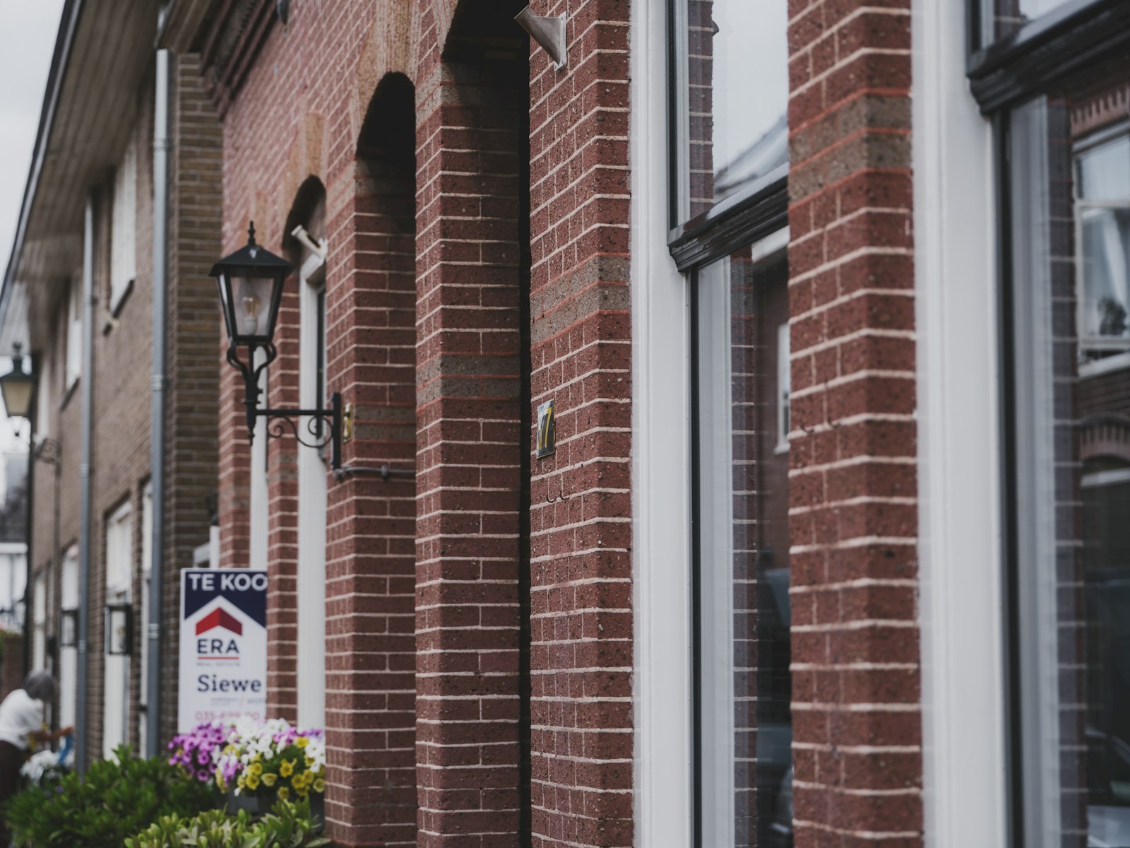 Nederlandse straat met een te-koop-bord van een makelaar, illustratief bij het biedingsproces op de woningmarkt