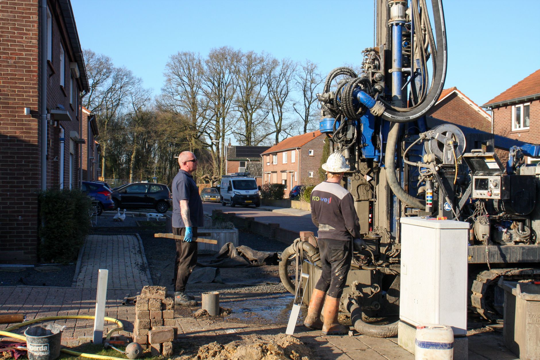 Bouwvakkers aan het werk met boorapparatuur in een Nederlandse woonstraat, illustratief voor de bouwsector en bpfBOUW