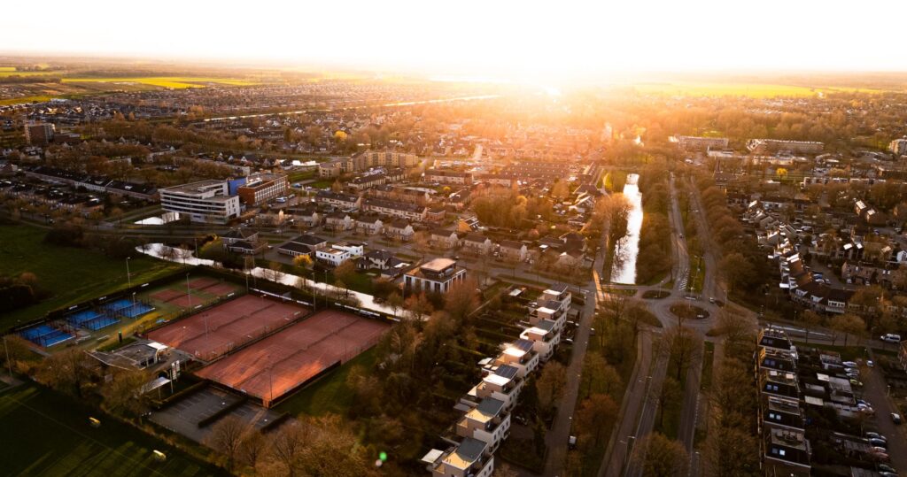Luchtfoto van een Nederlandse gemeente bij zonsondergang, illustratief bij de huizenprijzen per gemeente