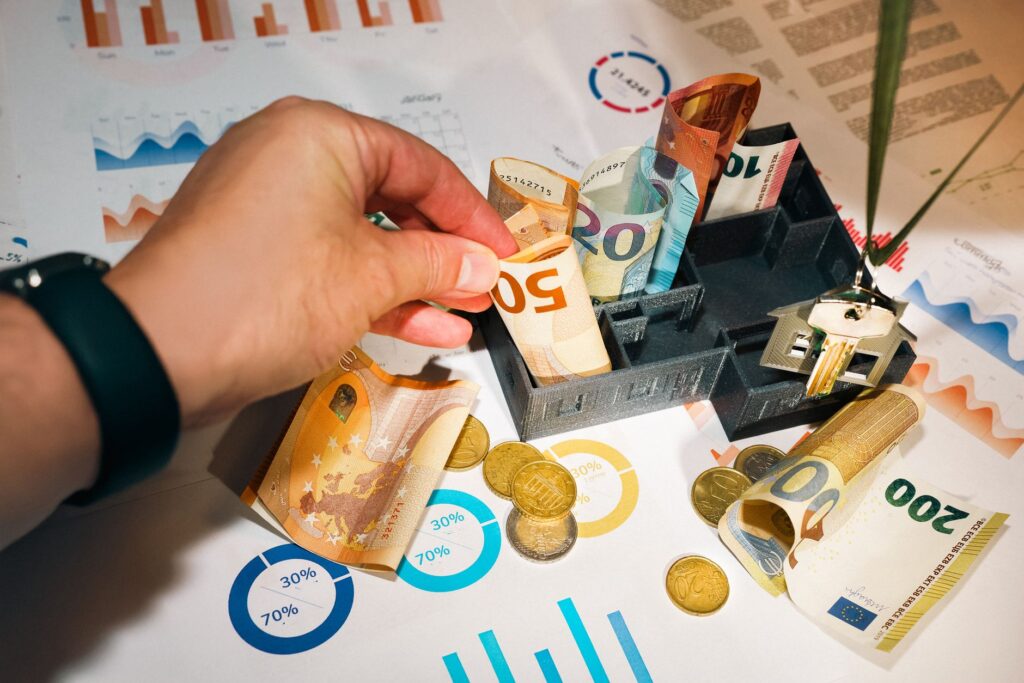 Eurobiljetten, munten en grafieken naast een maquettewoning als beeld bij de hypotheekrente