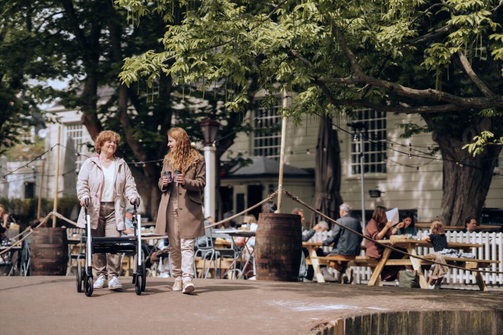 Oudere vrouw met rollator wandelt door een Nederlandse straat, beeld bij zorgvastgoed in Brabant