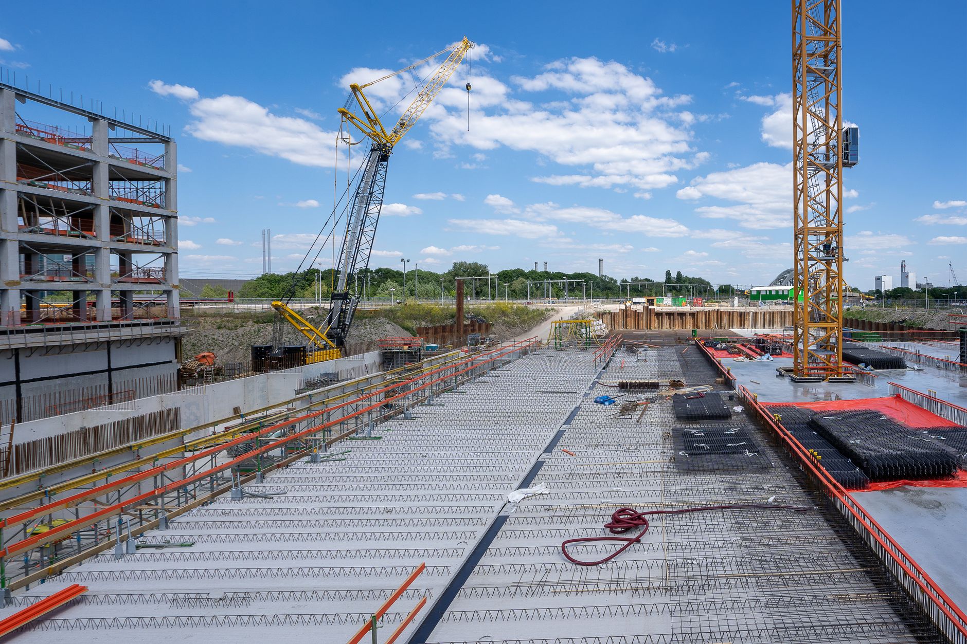 Bouwplaats van een groot distributiecentrum met kranen en een gestorte vloer, vergelijkbaar met de bouw in Hoogeveen