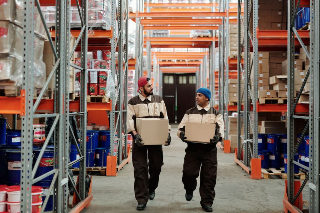 Medewerkers dragen dozen door een gangpad van een distributiecentrum, beeld bij het nieuwe distributiecentrum in Lelystad