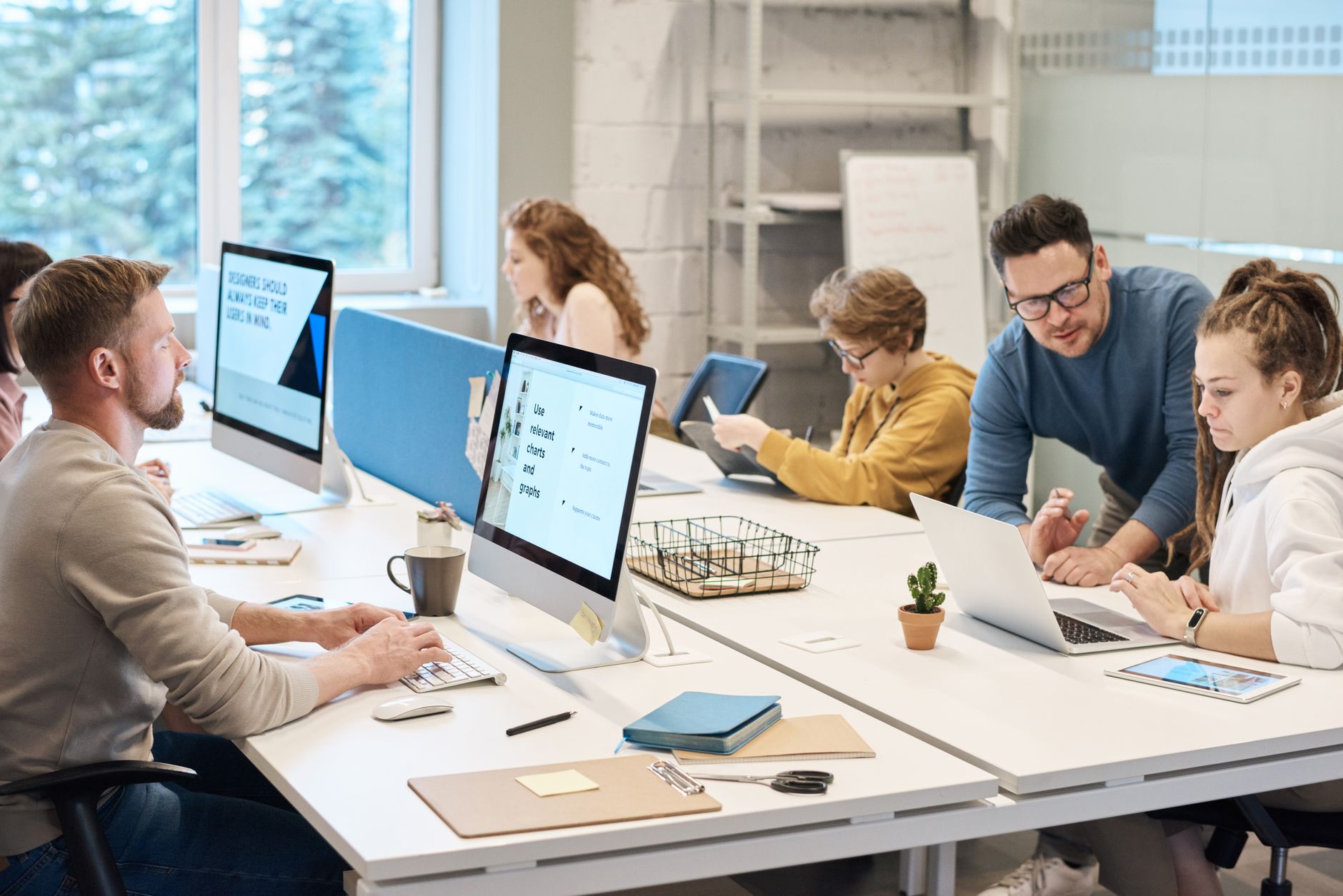 Medewerkers van een mkb-bedrijf werken samen aan bureaus in een goed bezette kantoorruimte