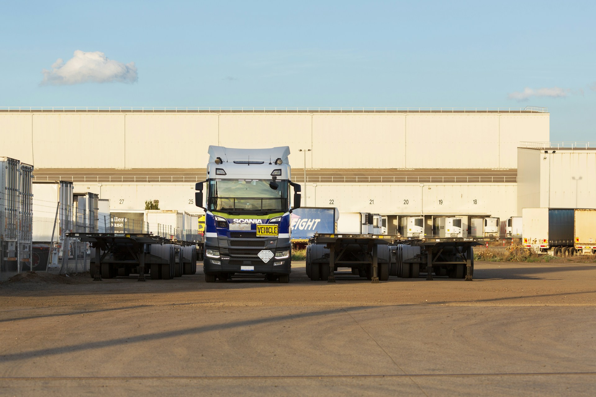 Vrachtwagen en opleggers voor een distributiecentrum, beeld bij de herfinanciering van het logistiek fonds van Delin