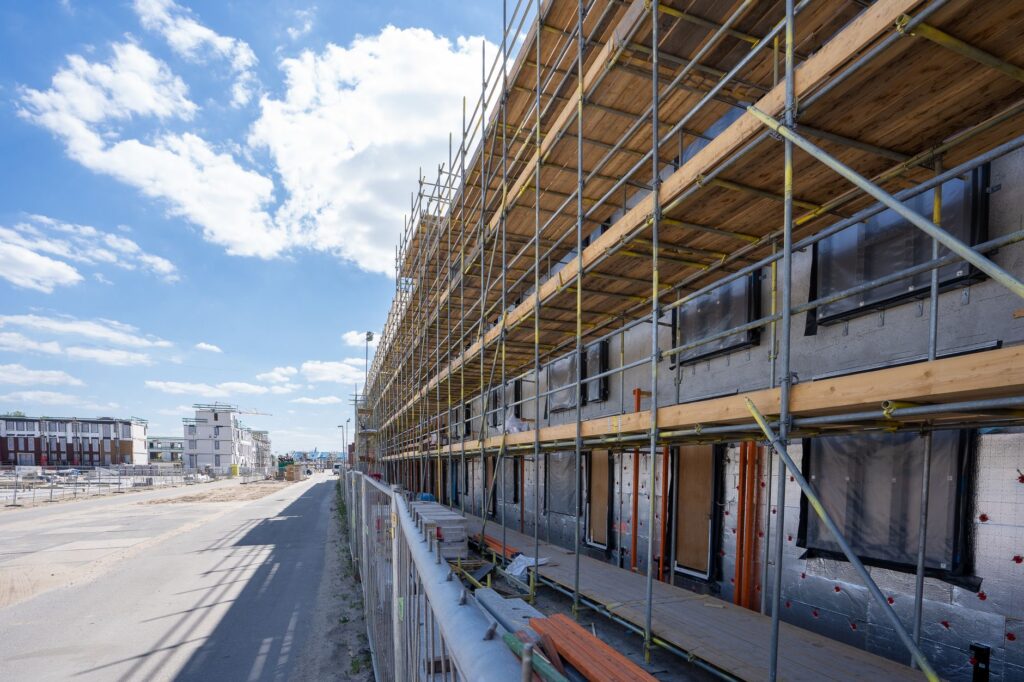 Nieuwbouwwoningen in aanbouw achter steigers, beeld bij netcongestie Brabant en woningbouw