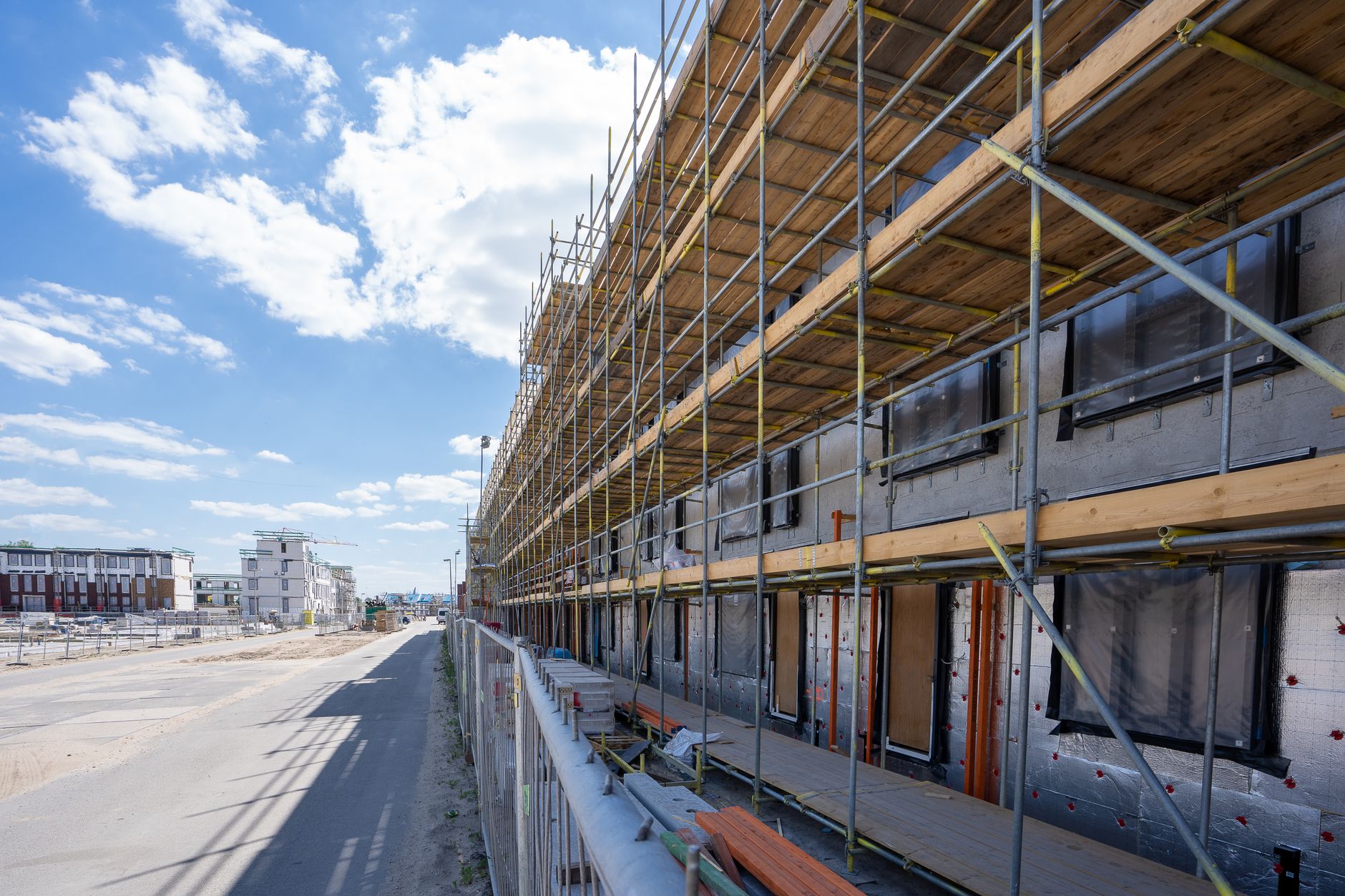 Nieuwbouwwoningen in aanbouw achter steigers, beeld bij netcongestie Brabant en woningbouw