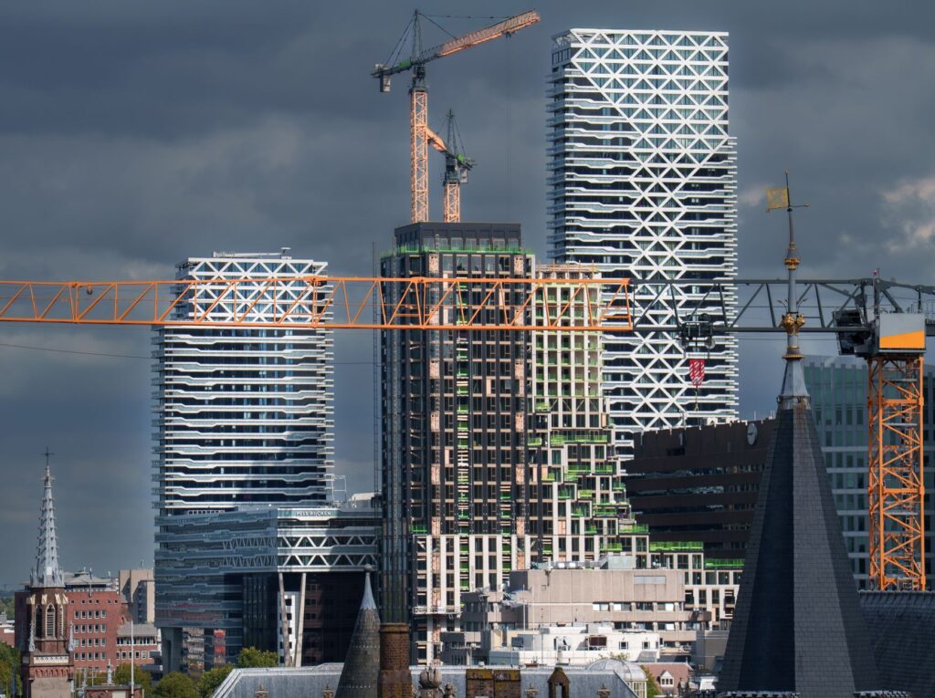 Bouwkranen en woontorens in aanbouw in de skyline van Den Haag, symbool voor de versnelling van de woningbouw