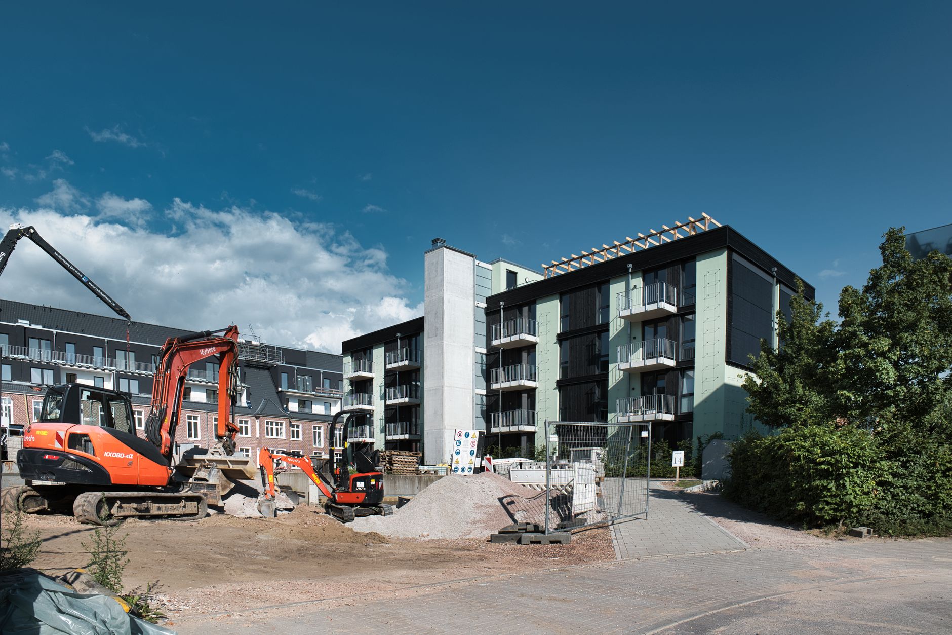 Bouwplaats met graafmachines naast nieuwe appartementen in aanbouw