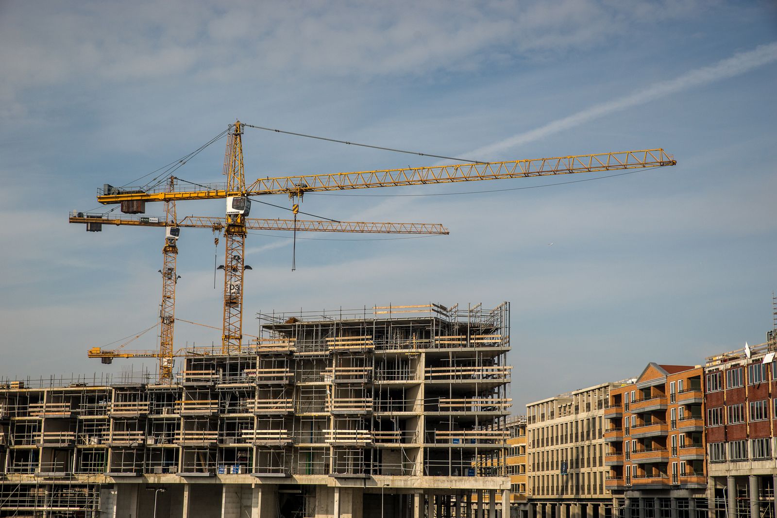 Bouwplaats met torenkranen en een appartementencomplex in aanbouw, beeld bij de financiering van woningcorporaties