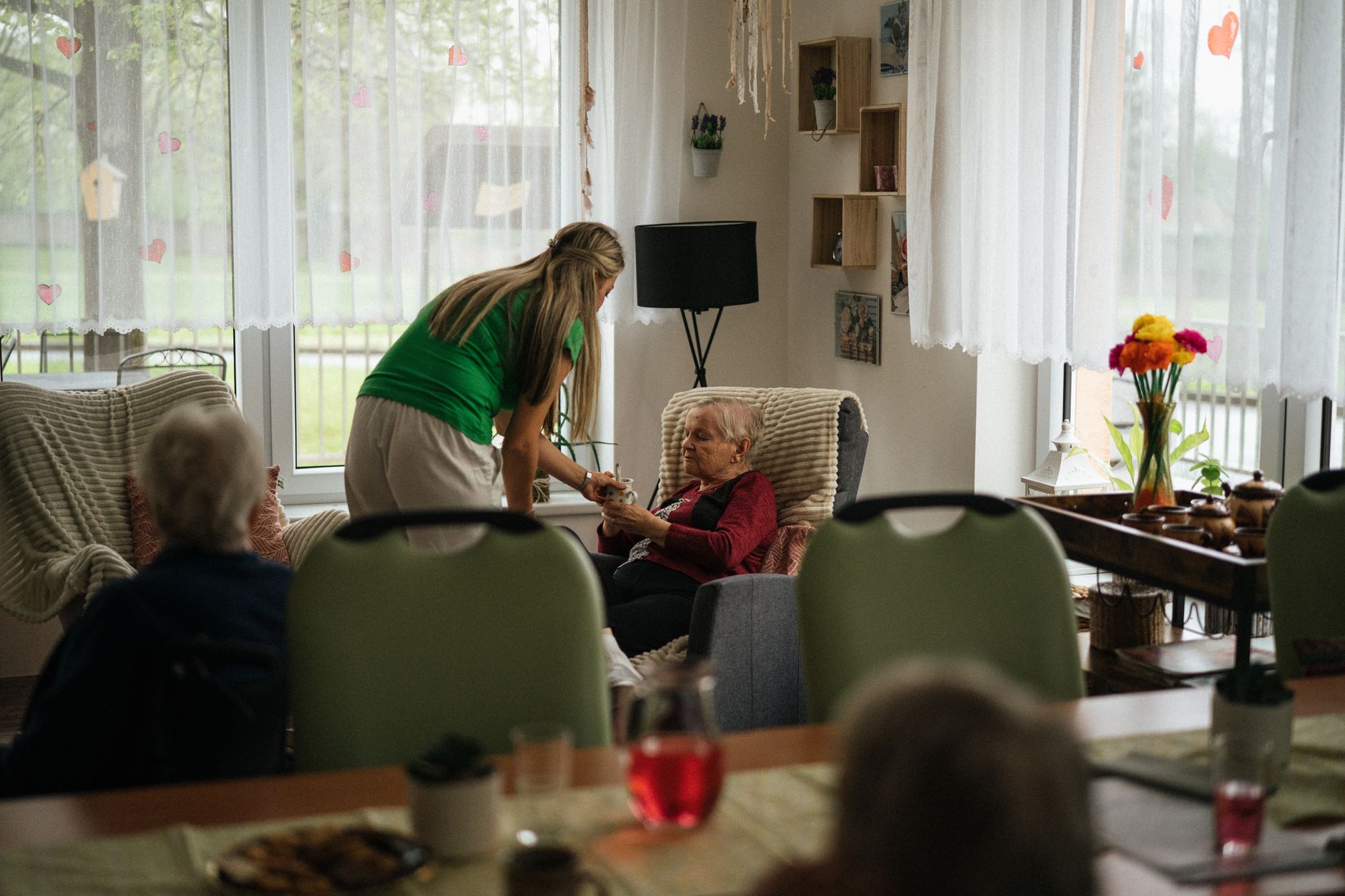 Zorgvastgoed: zorgmedewerker bij bewoners in de huiskamer van een kleinschalig verpleeghuis