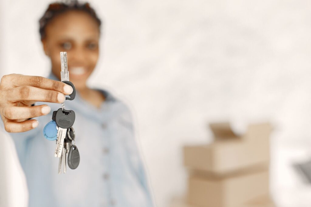 Vrouw toont de sleutels van haar nieuwe woning, illustratief bij de groei van alleenstaande kopers