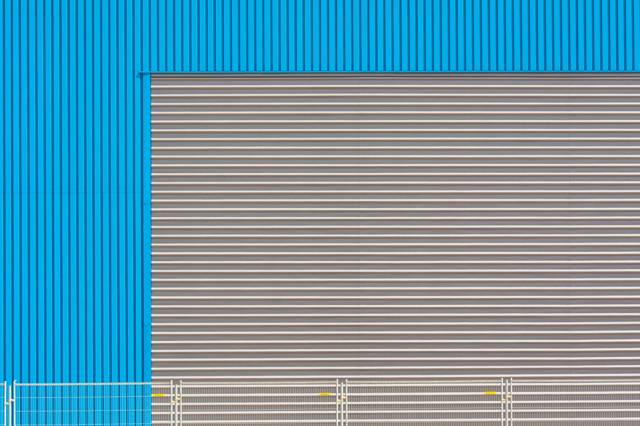 Blauwe gevel van een bedrijfshal met roldeur, illustratief bij nieuwe bedrijfsruimte in Oosterhout