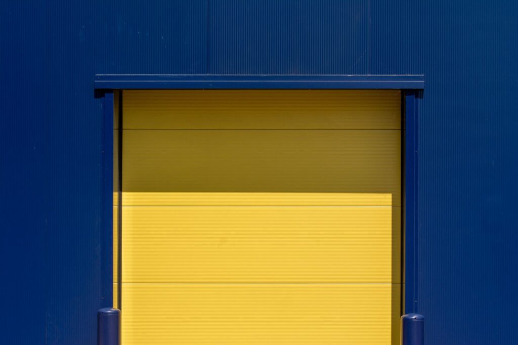 Gele overheaddeur van een laaddock in een blauwe metalen gevel van een bedrijfspand