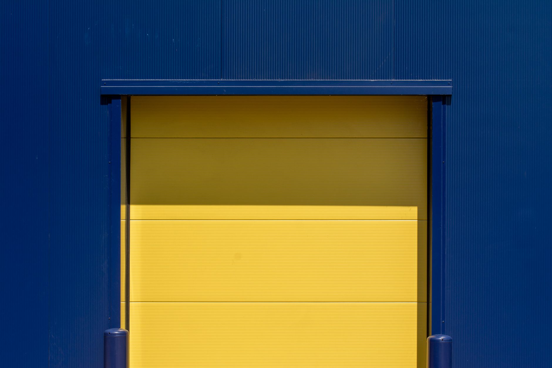 Gele overheaddeur van een laaddock in een blauwe metalen gevel van een bedrijfspand