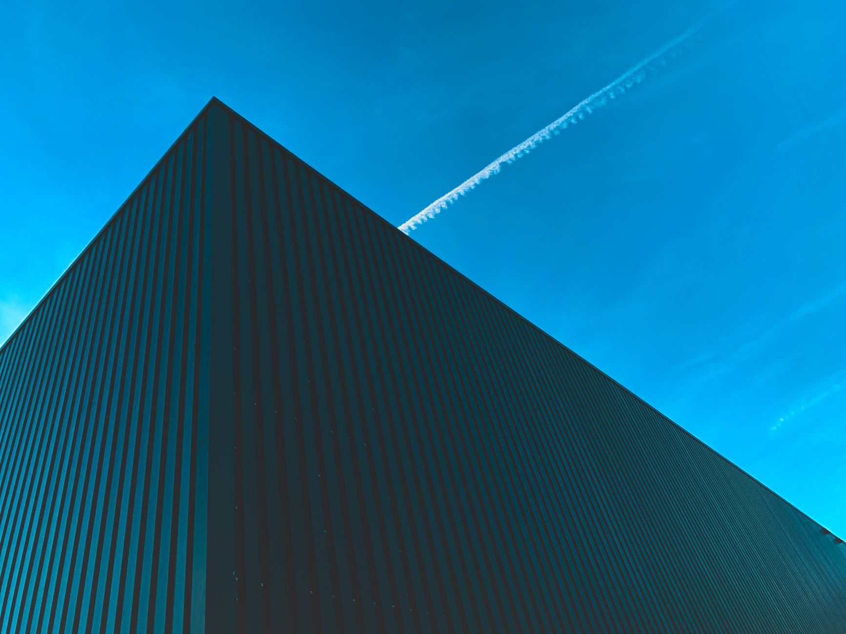 Gevel van een modern logistiek gebouw met golfplaat tegen een blauwe lucht