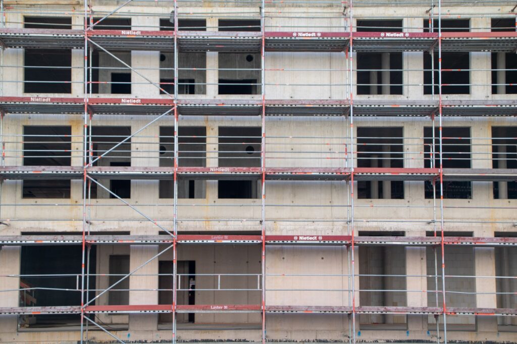 Woongebouw in aanbouw achter steigers, illustratief bij het Nationaal Expertisecentrum Woningbouw