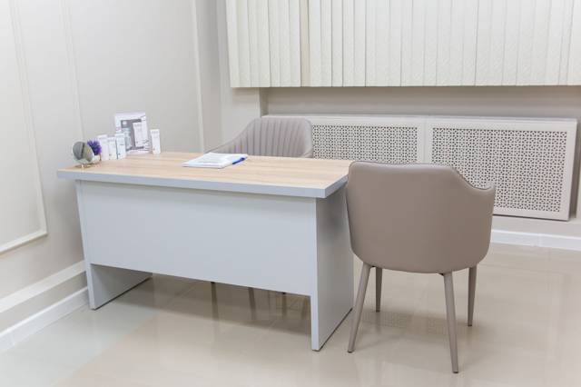 Lichte spreekkamer met bureau en stoelen, illustratief bij de aankoop van gezondheidscentra in Ede en Twello