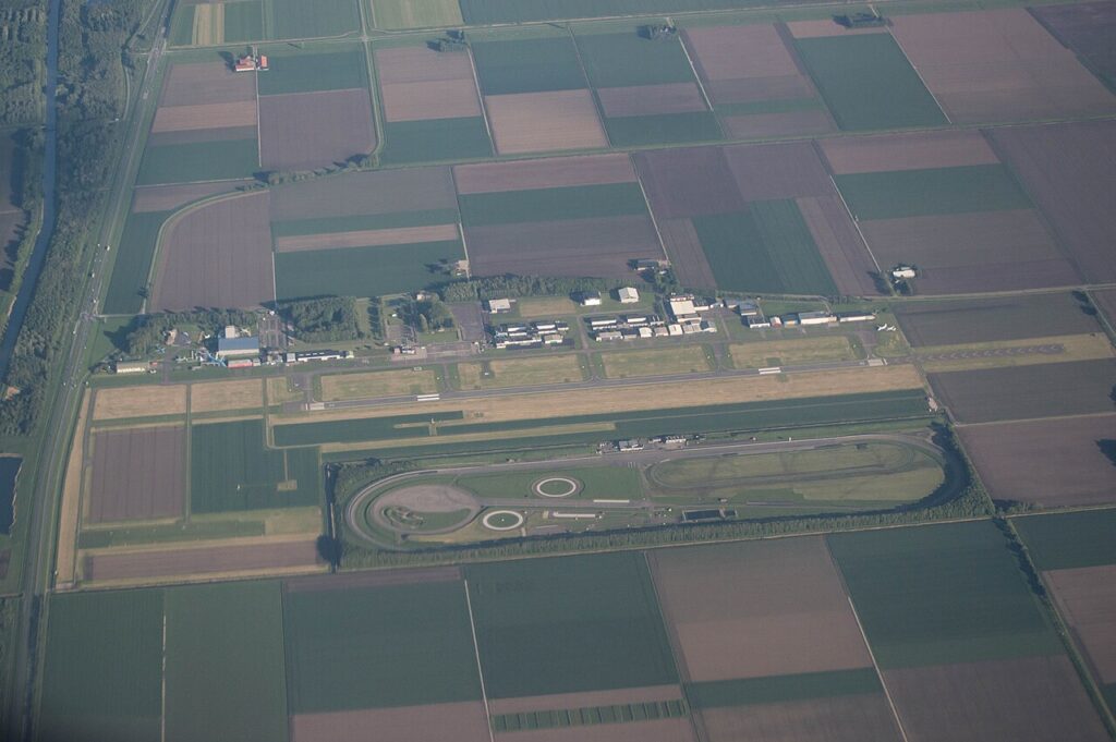 Luchtfoto van Lelystad Airport met de start- en landingsbaan, het circuit en omliggende akkers