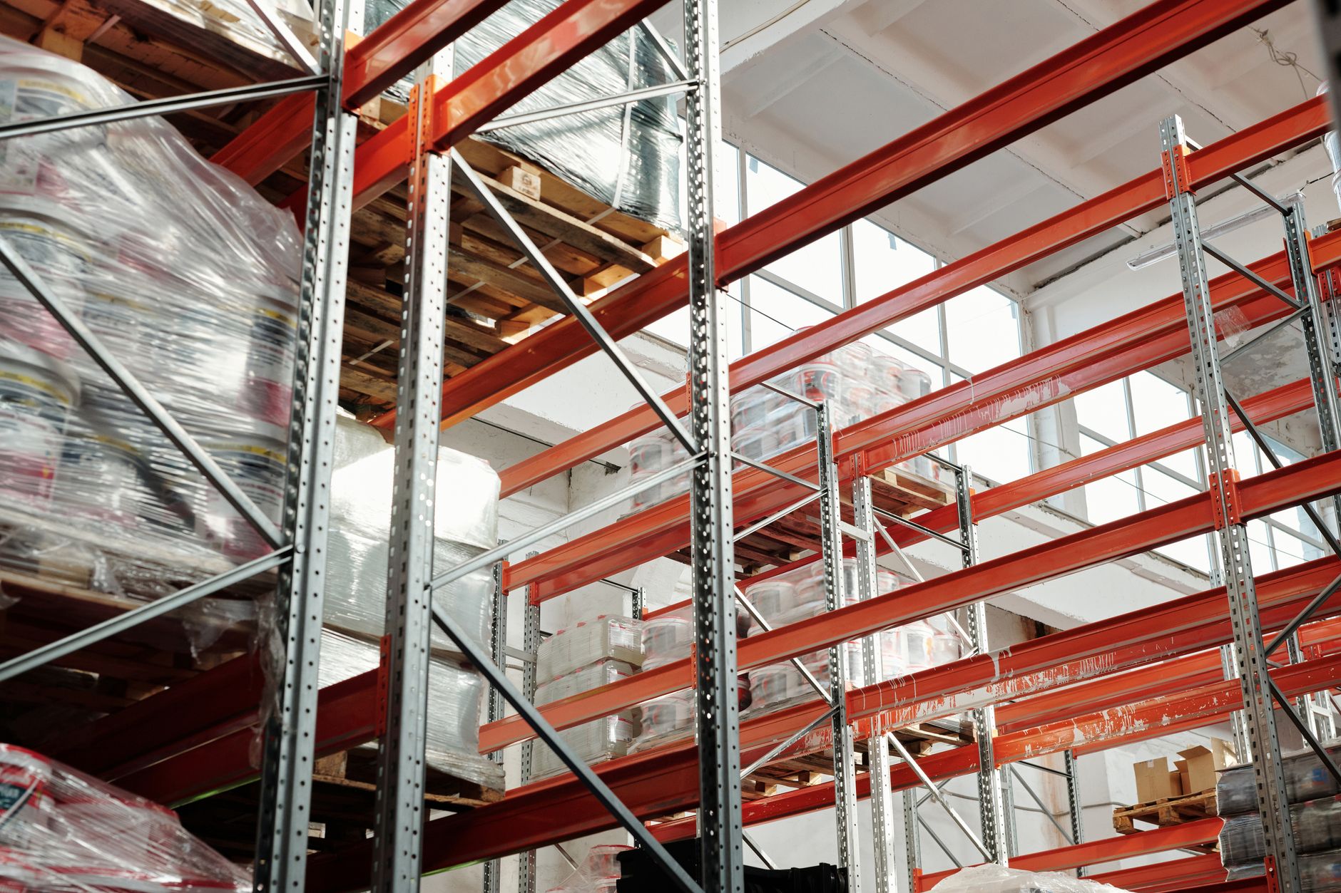 Palletstellingen met oranje liggers en in folie verpakte goederen in een licht warehouse