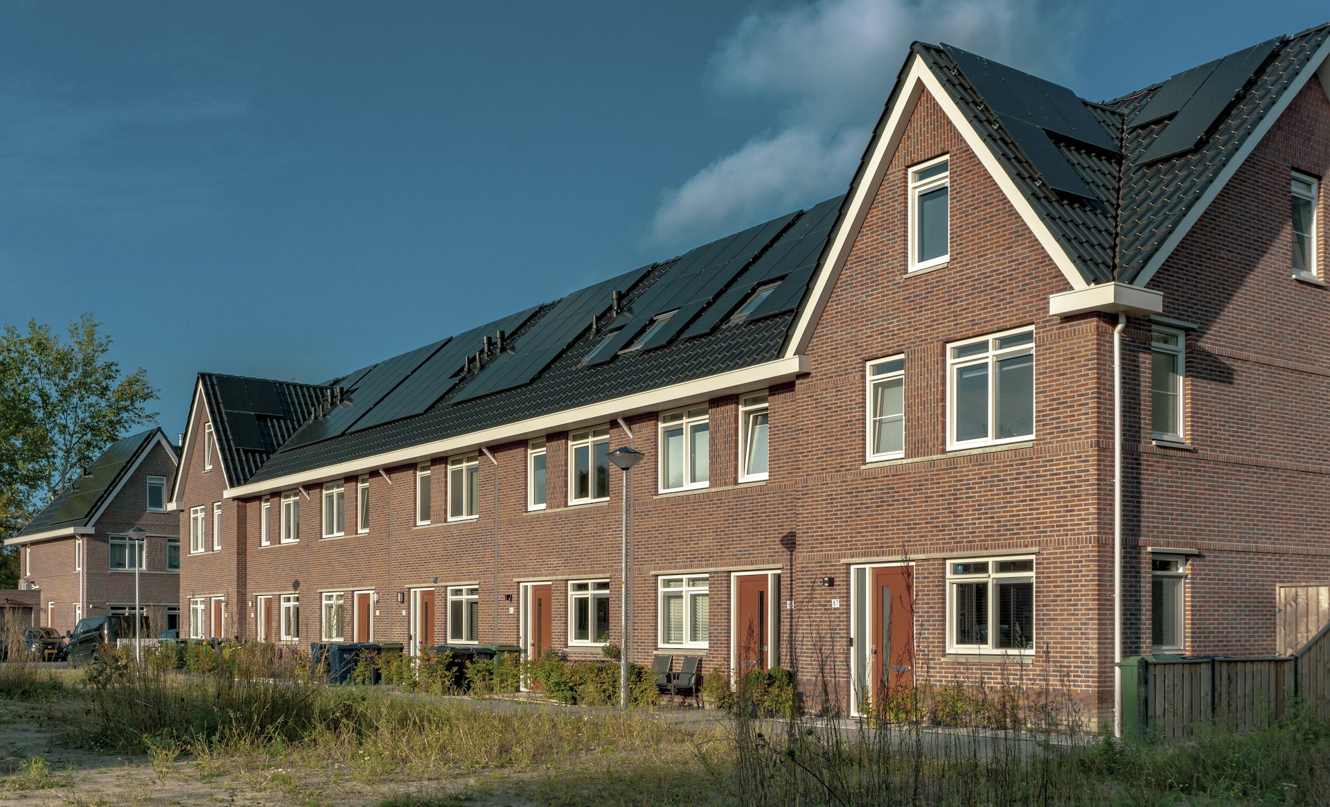 Nieuwe bakstenen rijwoningen met zonnepanelen op het dak in een Nederlandse nieuwbouwwijk