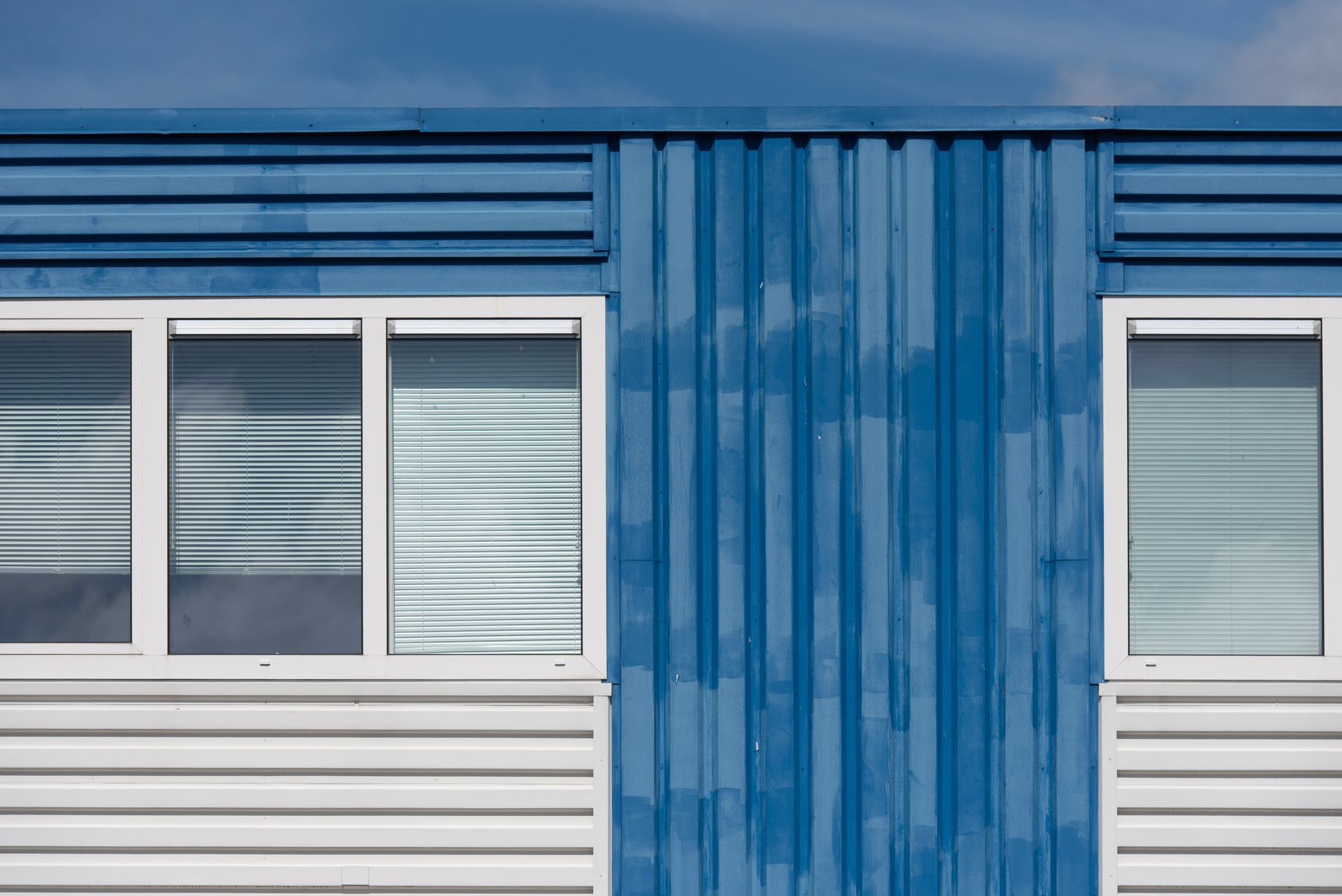 Gevel van een bedrijfspand met kantoorruimte en blauwe damwandplaten