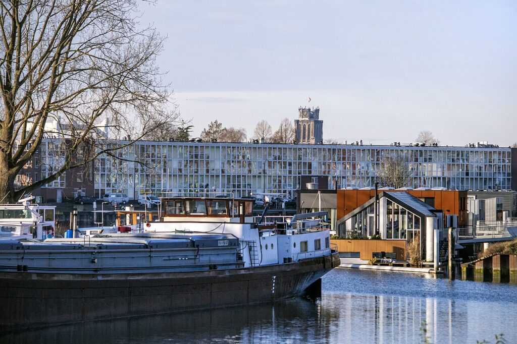 Nieuwbouw aan het water in de Dordtse Stadswerven met een binnenvaartschip en de toren van de Grote Kerk op de achtergrond