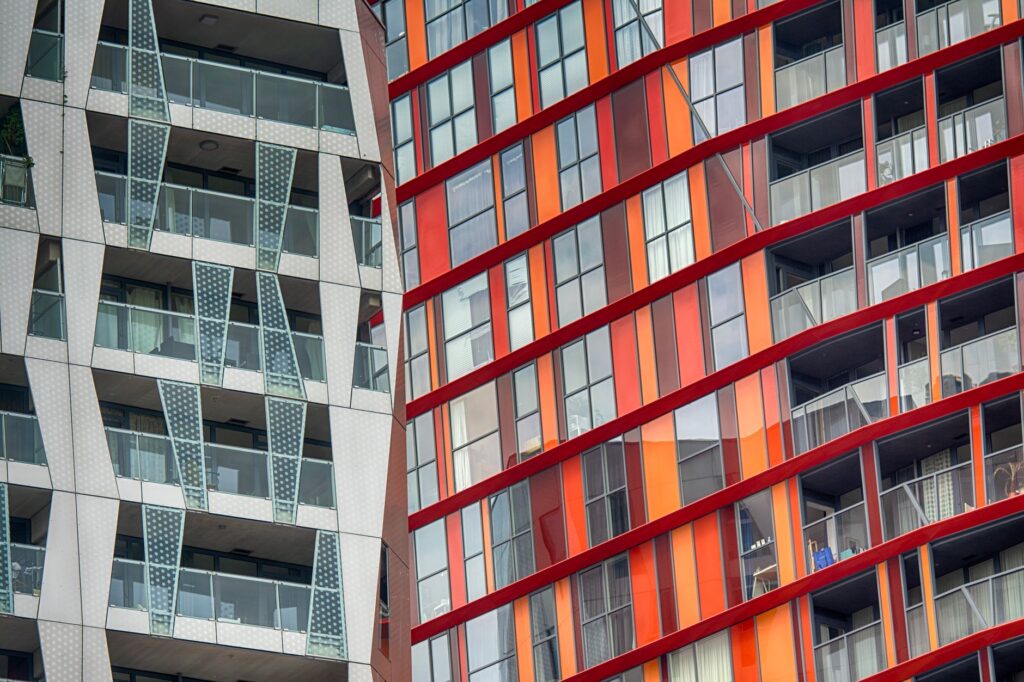 Gevels van moderne woontorens met balkons en rood-oranje panelen in het centrum van Rotterdam