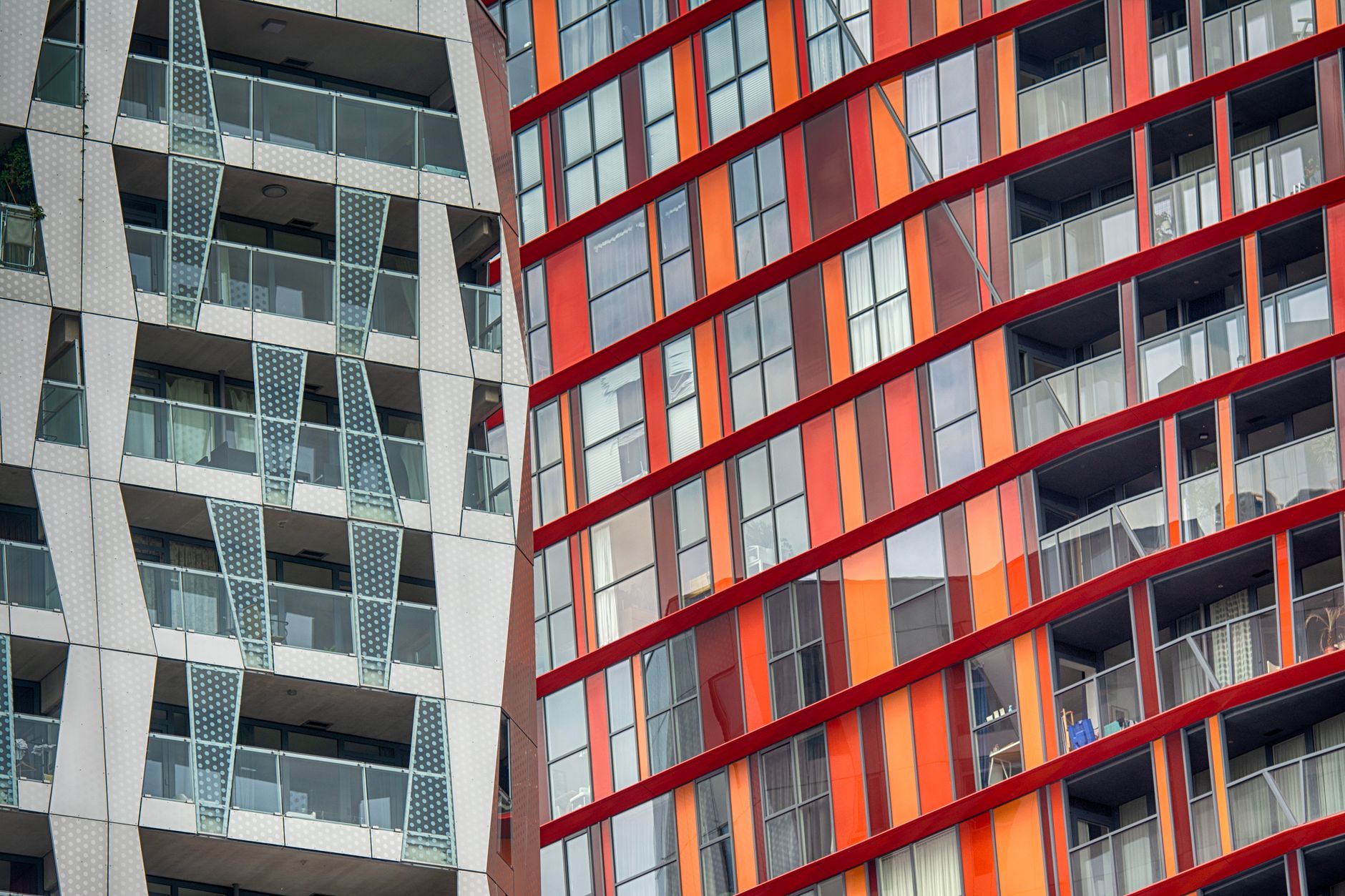 Gevels van moderne woontorens met balkons en rood-oranje panelen in het centrum van Rotterdam
